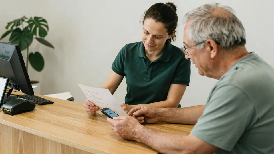Au comptoir du cabinet, une kinésithérapeute explique un document à un patient